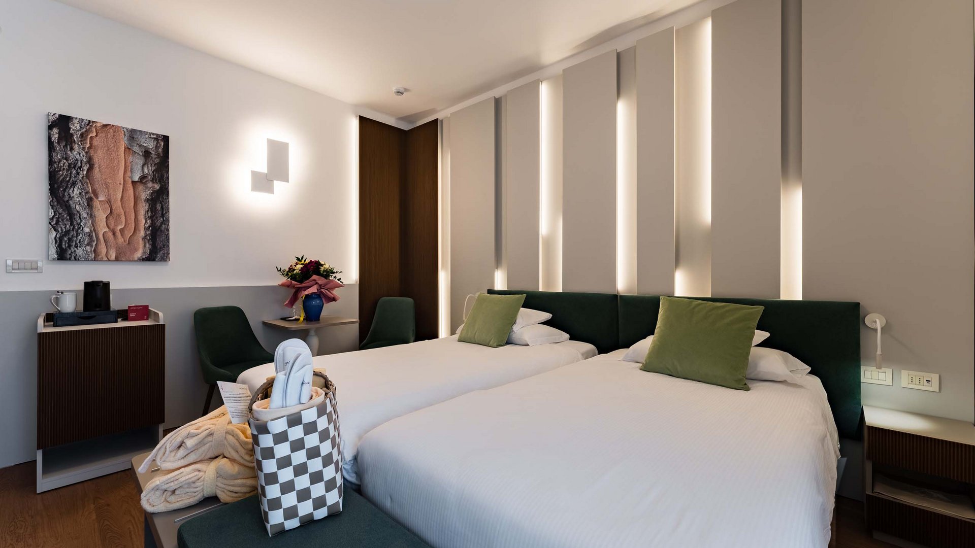 Wellness in Montegrotto: die Inklusivleistungen Modernes Zimmer mit zwei Einzelbetten, grünen Kissen und stilvoller Einrichtung